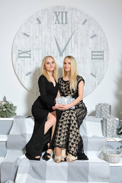Two young blonde twin sisters give each other Christmas presents - Φωτογραφία, εικόνα