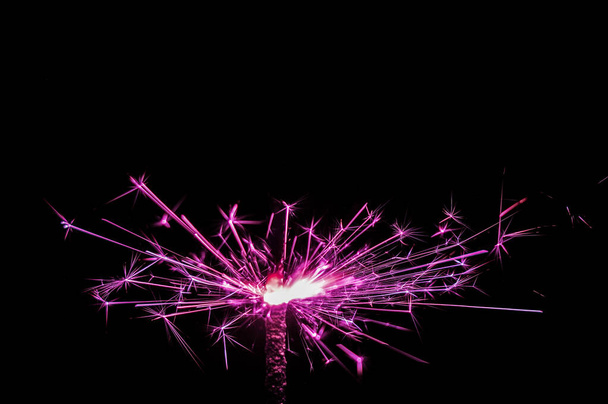 Sparkler in pink and white light on a black background.  - Fotó, kép