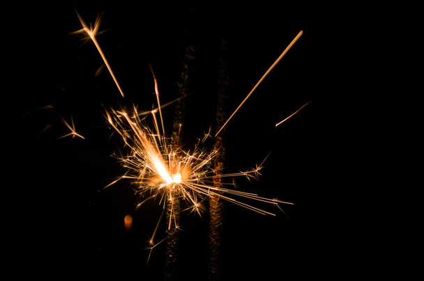 Sparkler in yellow and orange light on a black background.  - Foto, immagini
