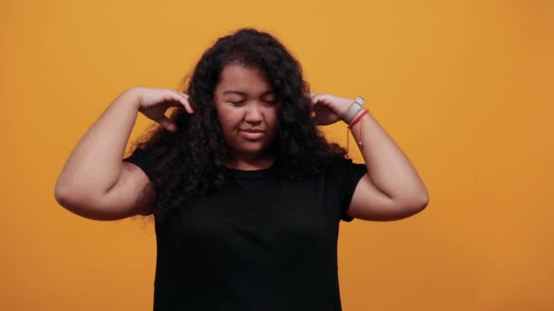Verwirrte Frau mit Übergewicht bedeckt Ohren mit Händen und sieht unzufrieden aus - Filmmaterial, Video