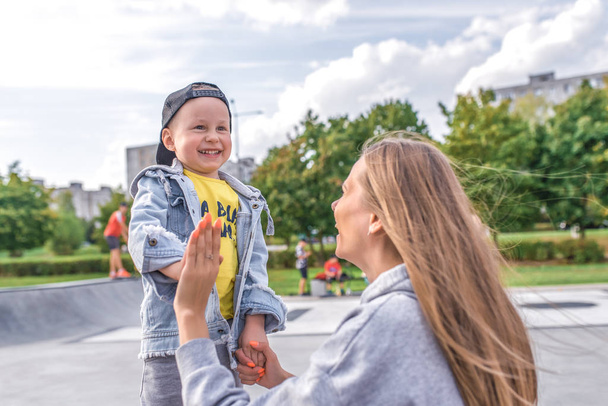 Happy family woman mom and little boy son, play and have fun, autumn day on street in city park. Emotions of joy of fun and relaxation weekend. Casual warm clothes denim t-shirt. - Foto, Bild