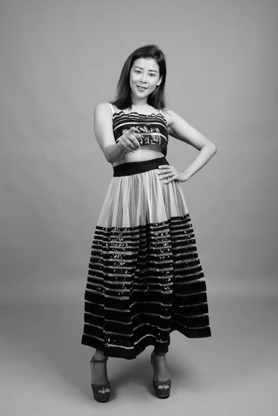 Young beautiful Asian woman against gray background - Foto, afbeelding
