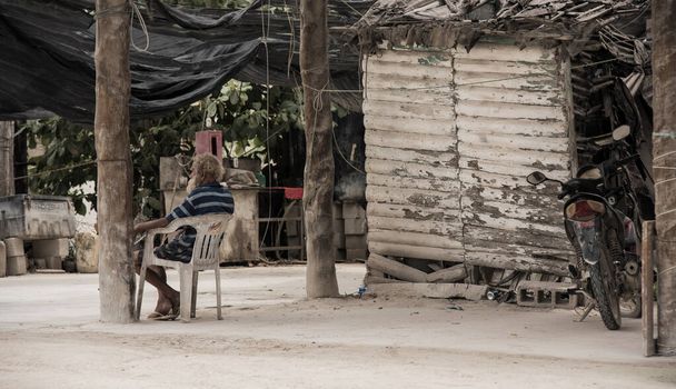 Holbox, Meksiko - kesäkuu 01,2017: vanha mies istuu varjossa talonsa vieressä
. - Valokuva, kuva