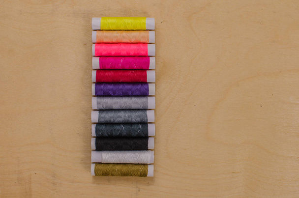 Разноцветные нити в катушках, швейный набор, комплект портного на светлом фоне. фон из дерева
 - Фото, изображение