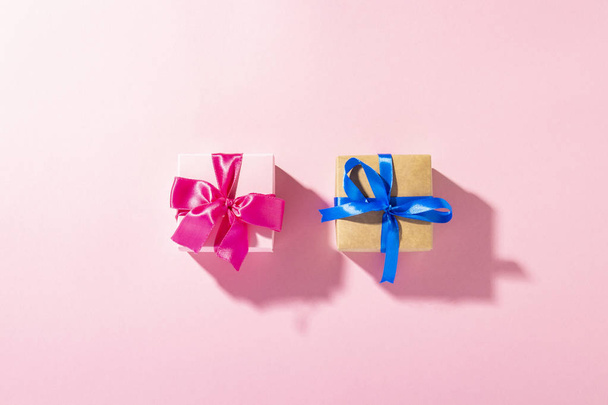 Gifts with a ribbon on a pink background under natural light. Modern. Concept holiday, family, beloved, for him. Banner. Flat lay, top view - 写真・画像