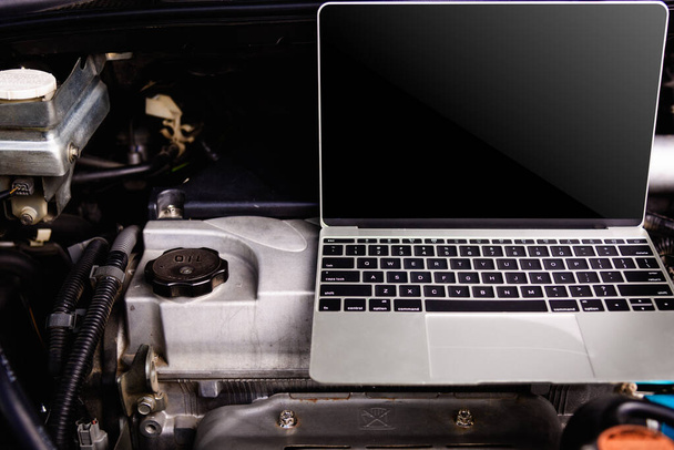 Ordenador portátil en el motor mecánico del coche para el servicio
 - Foto, imagen