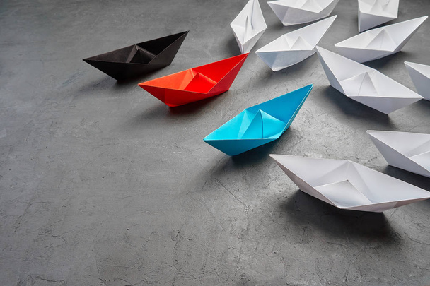 Conceito de liderança empresarial, barco de papel, a opinião-chave Líder, o conceito de influência.Conceito de negócio, barco de papel, a opinião-chave Líder, o conceito de influência.Barco de papel vermelho, azul e preto um
 - Foto, Imagem