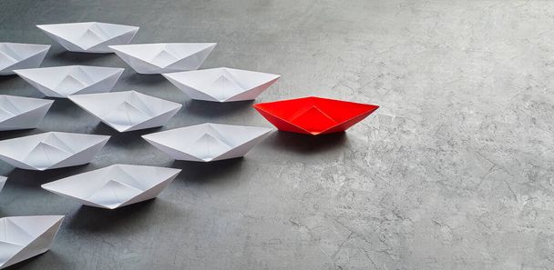 Üzleti vezetés koncepció, Paper Boat, a legfontosabb vélemény Leader, a koncepció a befolyás. Egy piros papírhajó, mint a vezető, amely a fehér hajók felé vezet szürke beton alapon, c - Fotó, kép