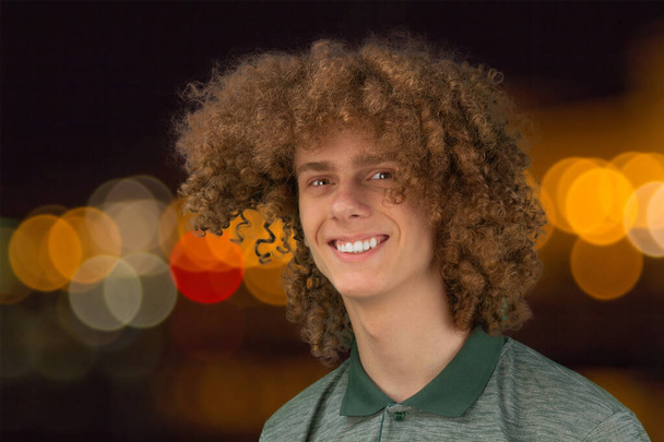 Celebration, people and holidays concept - happy curly guy having a Christmas or New Year party on the background of festive lights. - Fotografie, Obrázek