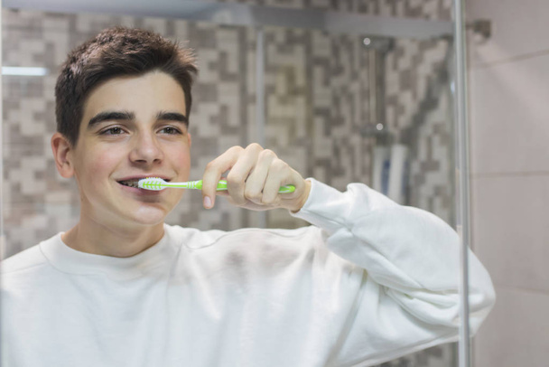 young teenage man with orthodontics brushing her teeth - Fotó, kép