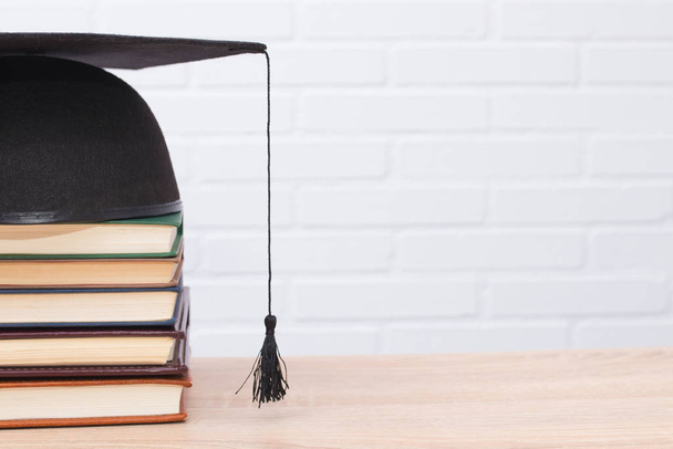 graduation cap and books on wood and white background - Φωτογραφία, εικόνα