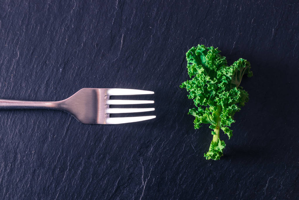 green vegetable leaf with fork isolated on stone - Foto, afbeelding