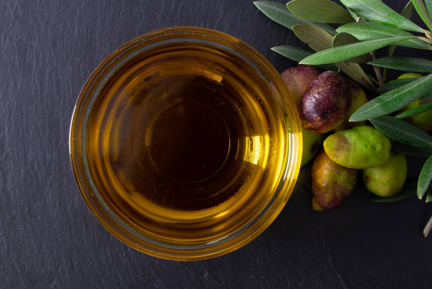 recipiente de vidro com azeite virgem extra e azeitonas naturais com ramos de azeitona
 - Foto, Imagem