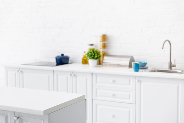 szelektív fókusz a modern fehér konyha belső konyhai eszközök közelében téglafal - Fotó, kép