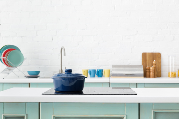 selectieve focus van moderne witte en turquoise keuken interieur met pot op elektrische inductie kookplaat - Foto, afbeelding