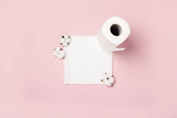 Papierhandtücher und Baumwollblumen auf rosa Hintergrund. Konzept ist 100 Naturprodukt, zart und weich. flache Lage, Draufsicht - Foto, Bild
