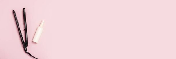 Haarglätter und Haarpflegemittel auf rosa Hintergrund. Konzept der Haarpflege, Frisur, Schönheitssalon, Friseur. flache Lage, Draufsicht. Banner - Foto, Bild