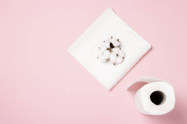Rolo de toalhas de papel e flores de algodão em um fundo rosa. Conceito é 100 produto natural, delicado e macio. Deitado plano, vista superior
 - Foto, Imagem