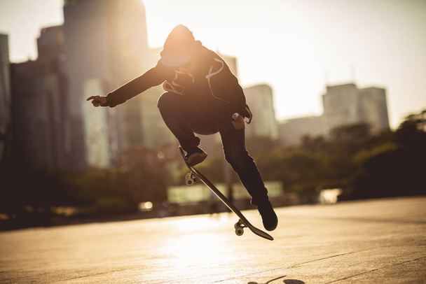 Female athlete skateboarding at sunset in urban city - Foto, imagen