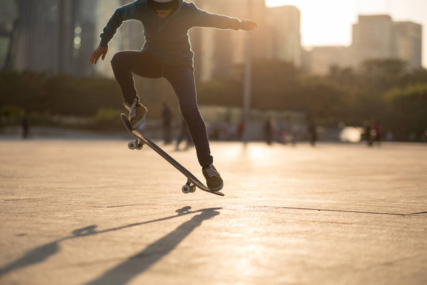 Female athlete skateboarding at sunset in urban city - Фото, зображення