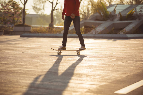 Unrecognizable woman skateboarding at sunset in urban city - Foto, imagen