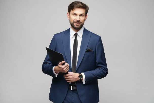 Portrait of a handsome young business man holding folder - 写真・画像