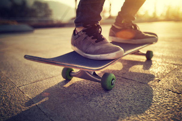 Feet of person skateboarding at sunset in urban Chinese city - Foto, imagen