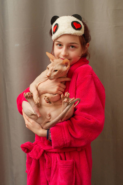 Φωτογραφία μιας αξιολάτρευτης νεαρής Καυκάσιας που αγκαλιάζει το χαριτωμένο κατοικίδιο της. Σφίγγα γάτα χωρίς γούνα γουργουρίζει στα χέρια - Φωτογραφία, εικόνα