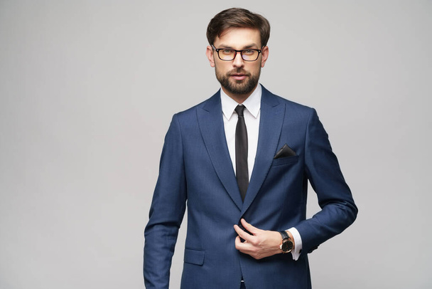 Portrait of a handsome young stylish businessman wearing glasses over grey background - Foto, Imagem
