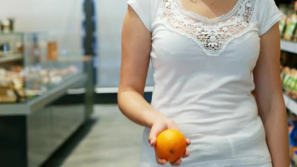 Kobiety ręka wymiotuje barwny pomarańczowy w supermarkecie w zwolnionym tempie - Materiał filmowy, wideo