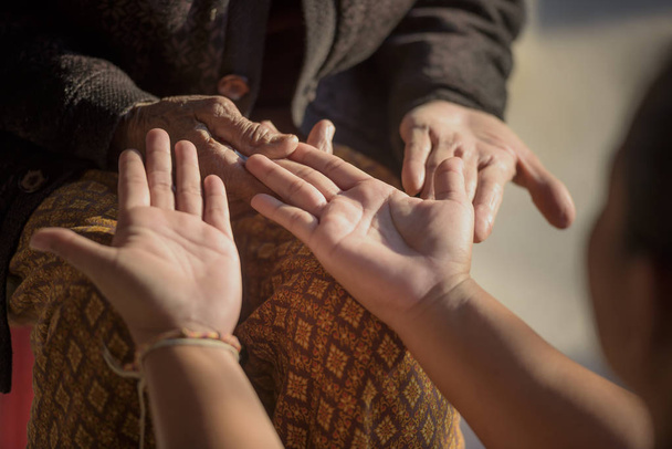 Νεαρή γυναίκα που κρατά τα χέρια της γιαγιάς της, άνθρωποι, οικογένεια και αγάπη έννοια. - Φωτογραφία, εικόνα