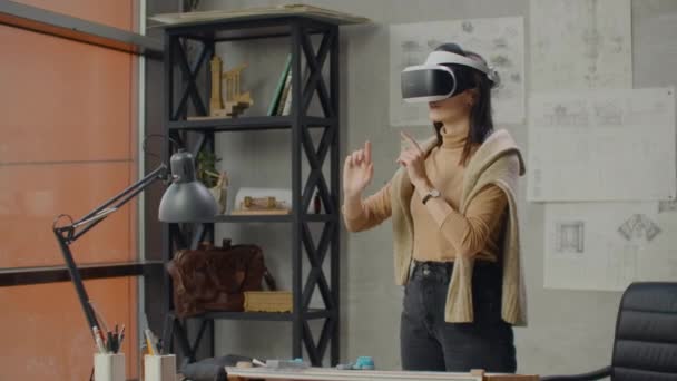 Engenheira no escritório em um capacete de realidade virtual usa gestos para gerenciar o projeto sem sair do escritório. Controlo de construção. Projeto de design do edifício e interior
. - Filmagem, Vídeo