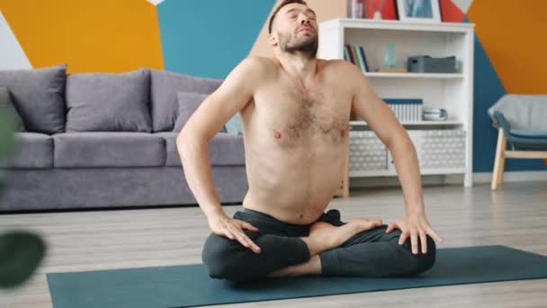 Lassú mozgás a férfi felnőtt csinál légzési gyakorlatok ül jóga mat otthon - Felvétel, videó