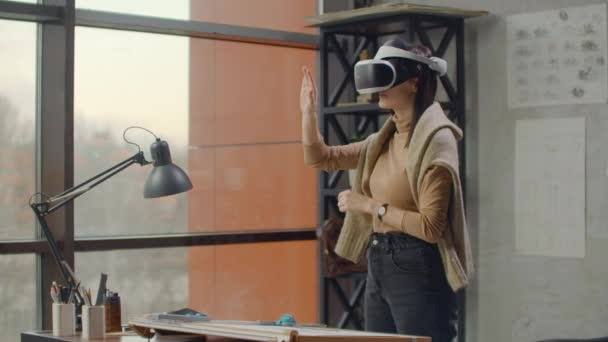 Engenheira-designer moderna no escritório com grandes janelas fica em um capacete de realidade virtual usa gestos para gerenciar o projeto sem sair do escritório. Controlo de construção. Projecto de concepção
 - Filmagem, Vídeo