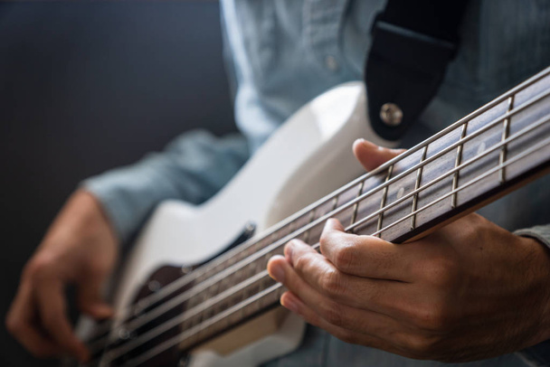 musician playing bass guitar finger style, closeup and selective focus- musical instrument for jazz, rock, blues, funk, hip hop music - Foto, imagen