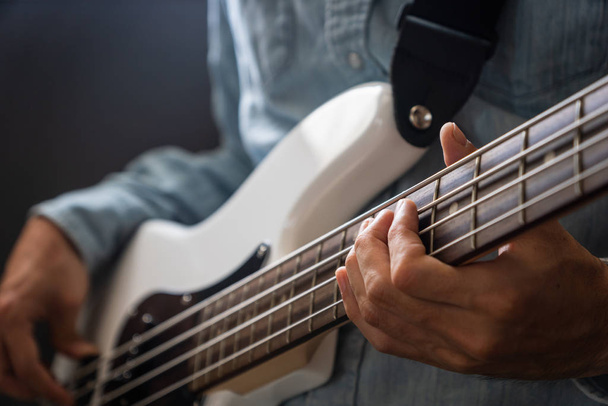 musician playing bass guitar finger style, closeup and selective focus- musical instrument for jazz, rock, blues, funk, hip hop music - Фото, изображение