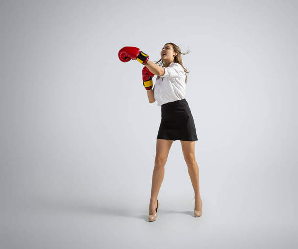 Caucasian woman in office clothes boxing isolated on grey studio background - Photo, image