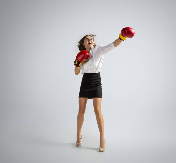Caucasian woman in office clothes boxing isolated on grey studio background - Foto, immagini