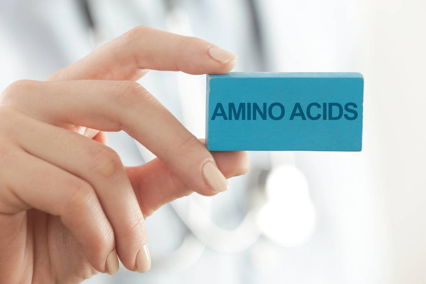 Doctor advises. Medical worker holds AMINO ACIDS signs. - Photo, Image
