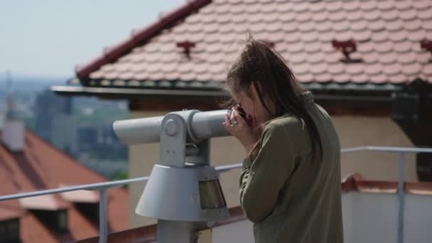 vrouw kijkt naar bezienswaardigheden van de stad met een telescoop - Video