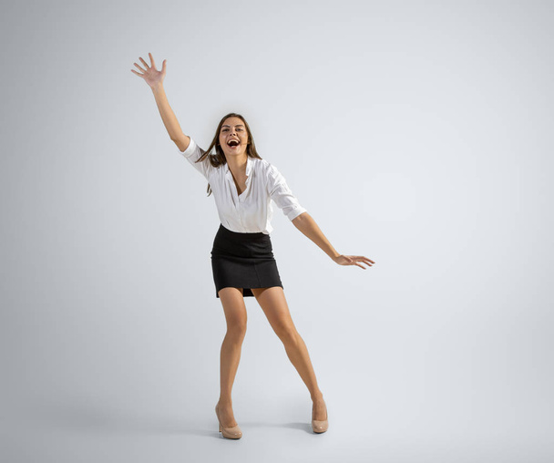 Caucasian woman in office clothes catching ball isolated on grey studio background - Photo, Image