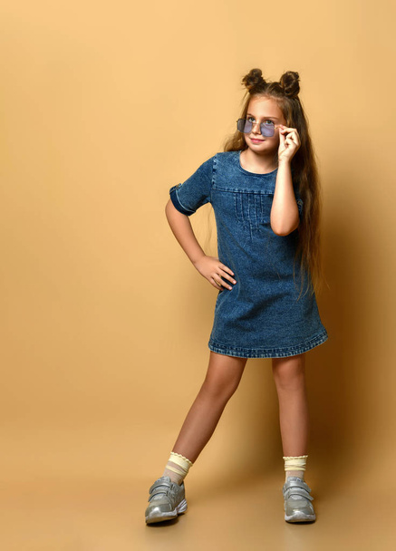 Cute girl in jeans sundress and sunglasses posing on camera. - 写真・画像