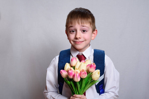 Studente con una borsa della scuola che tiene un mazzo di tulipani. Fondo bianco
 - Foto, immagini