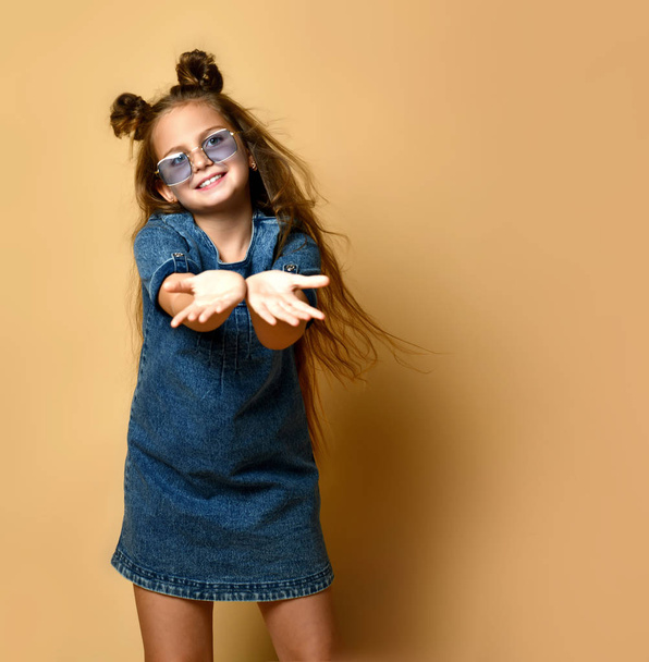 Cute girl in jeans sundress and sunglasses posing on camera. - Valokuva, kuva