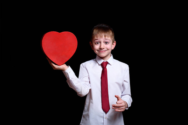 Ragazzo sorridente con una scatola rossa a forma di cuore. Isolato su sfondo nero
 - Foto, immagini