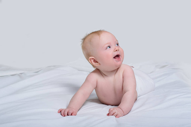 Um bebé sorridente na barriga. Olhando para cima com expressão surpresa. Fundo branco
 - Foto, Imagem
