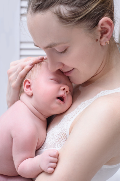 彼女の腕の中で金髪の眠っている赤ん坊を持つ母、優しさの瞬間。閉鎖 - 写真・画像