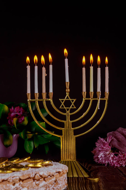 Festive menorah with white burning candles and cake with chocolate coins on the top. - Photo, Image