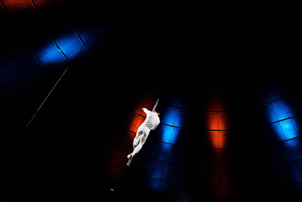 achteraanzicht van acrobat optredend op paal in arena van circus  - Foto, afbeelding