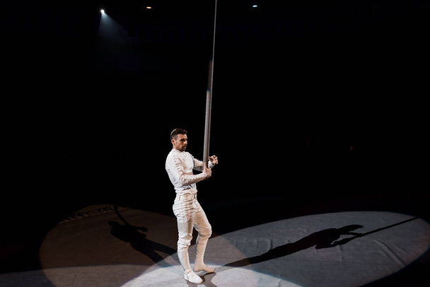 handsome acrobat standing near metallic pole in circus  - Photo, Image